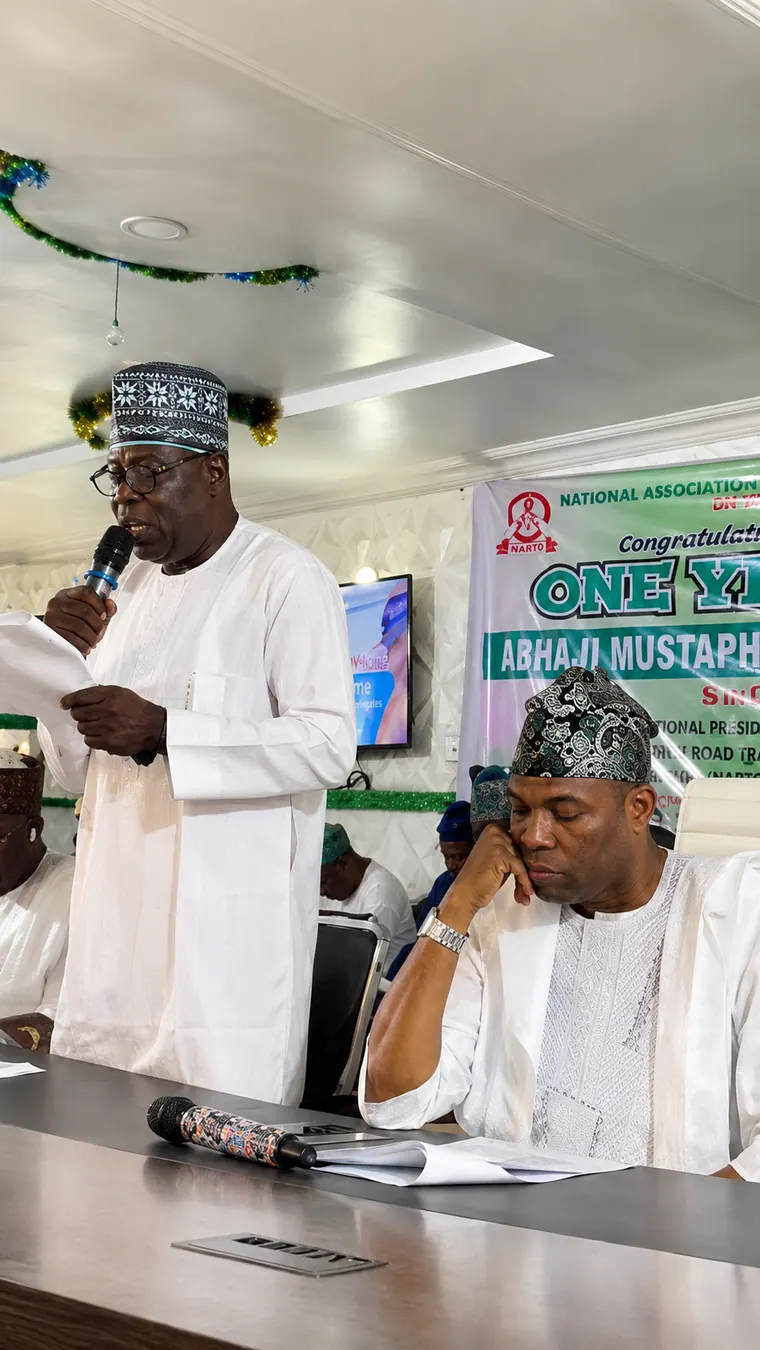 A staff member addressing members with the chairman seated nearby.